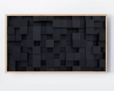 an abstract black art piece hanging on the wall in front of a white wall that has squares and rectangles all over it