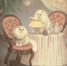 two white cats sitting at a table with a cake and teapot on it's side