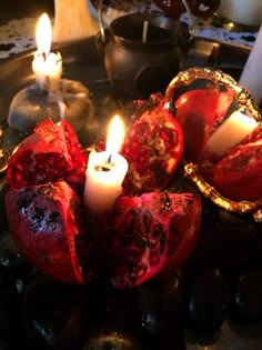 a candle is lit in the middle of some pomegranates