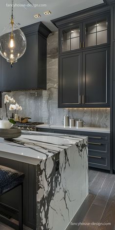 a kitchen with black cabinets and marble counter tops, an island in the foreground