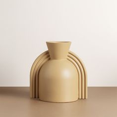 a beige vase sitting on top of a table next to a stack of smaller ones