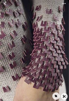 a woman's hand holding onto a purple and white dress with spikes on it