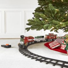 a toy train set sitting on top of a white rug next to a christmas tree