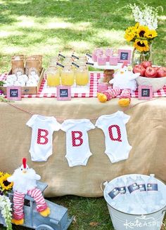 a baby shower is set up outside on the grass with food and drinks in buckets