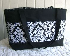 a black and white tote bag sitting on top of a bed