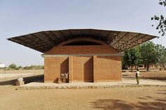 a man standing in front of a red brick building with a roof over it's entrance