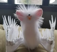 a stuffed animal with white feathers on it's head and arms, sitting on a couch