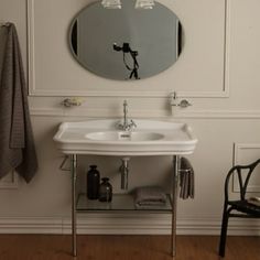 a white sink sitting under a bathroom mirror next to a black chair with a towel on it