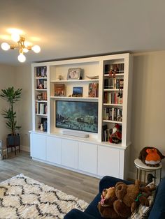 a living room filled with furniture and a flat screen tv on top of a white entertainment center