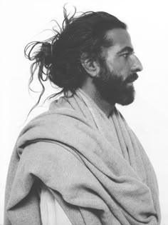 a black and white photo of a man with long hair wearing a shawl over his shoulders