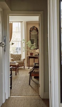 an open door leading to a living room with chairs and a mirror on the wall