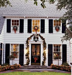 a white house decorated for christmas with wreaths and lights