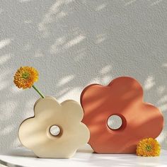 two flower vases sitting on top of a white table with yellow flowers in them