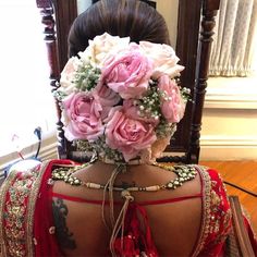 the back of a woman's head with flowers in her hair and jewelry around her neck