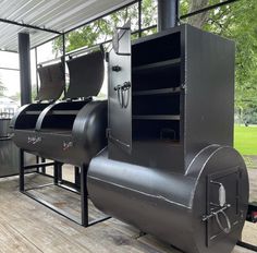 a large metal stove sitting on top of a wooden floor next to a building with lots of windows