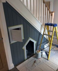 there is a dog house under the stairs with a ladder and paint rollers on it