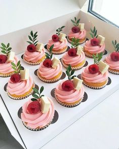 cupcakes with pink frosting and raspberry toppings are arranged on a table