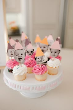 some cupcakes with faces on them are sitting on a cake plate in front of a mirror