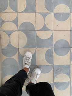 a person standing on a tiled floor with white shoes