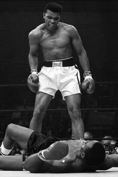 a black and white photo of a man on the ground with boxing gloves over his head