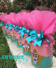 pink and blue tin canisters with bows on the top are sitting in grass