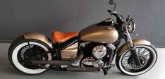 a gold motorcycle parked in a garage next to a gray wall with white rims