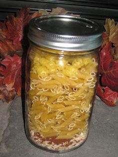 a jar filled with macaroni and cheese sitting on top of a counter next to autumn leaves