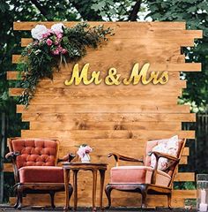 two chairs sitting next to each other in front of a wooden wall with mr and mrs written on it