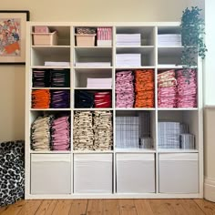 a white bookcase filled with lots of different types of folded paper and other items