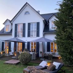 a large white house with blue shutters and an outdoor seating area in front of it