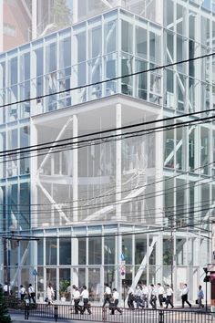 people are walking on the sidewalk in front of an office building with glass walls and balconies