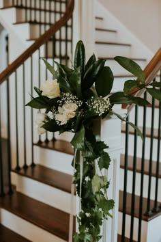 a bouquet of flowers sitting on top of a glass vase next to a stair case