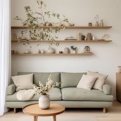 a living room filled with lots of furniture and shelves above the couch, on top of a hard wood floor