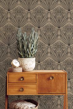 a wooden table with a plant on top of it next to a brown wallpaper