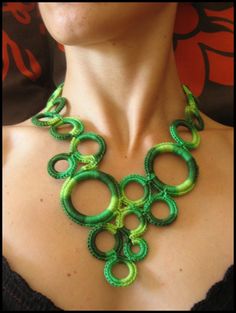 a woman wearing a green necklace with rings on it