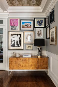 a living room with pictures on the wall and wood flooring in front of it