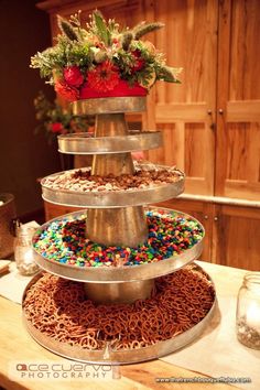 a three tiered cake with sprinkles and flowers on top is sitting on a table