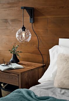 a lamp that is sitting on top of a table next to a bed with pillows