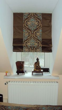 there is a small buddha statue on the window sill in this room with curtains