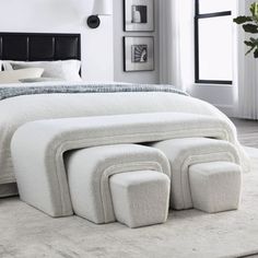 a white bed with four foot stools in front of the headboard and foot board