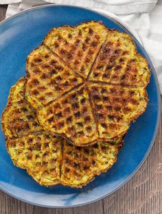 three waffles on a blue plate next to a cup of coffee and napkin