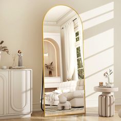 a large mirror sitting on top of a wooden floor next to a white couch and table