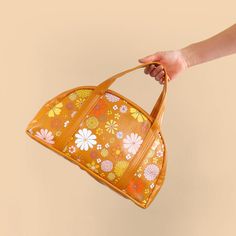 a woman's hand holding an orange purse with flowers on the inside and outside