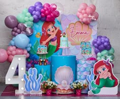 the birthday cake is decorated with ariel the mermaid decorations, balloons and paper cutouts