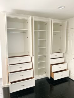 an empty walk in closet with white cabinets and drawers on black tile floored floors