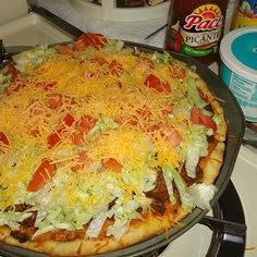 a pizza sitting on top of a pan covered in cheese and toppings next to an ice cream container