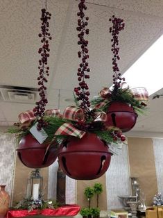 some red balls hanging from the ceiling with christmas decorations on them and ribbons tied to them