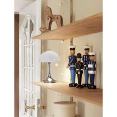 a shelf with wooden toy soldiers on it and a lamp in the corner next to it