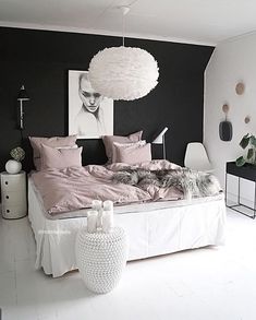 a bedroom with black and white walls, pink bedding and pictures on the wall