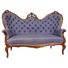 an antique style couch with wooden frame and blue upholstered fabric